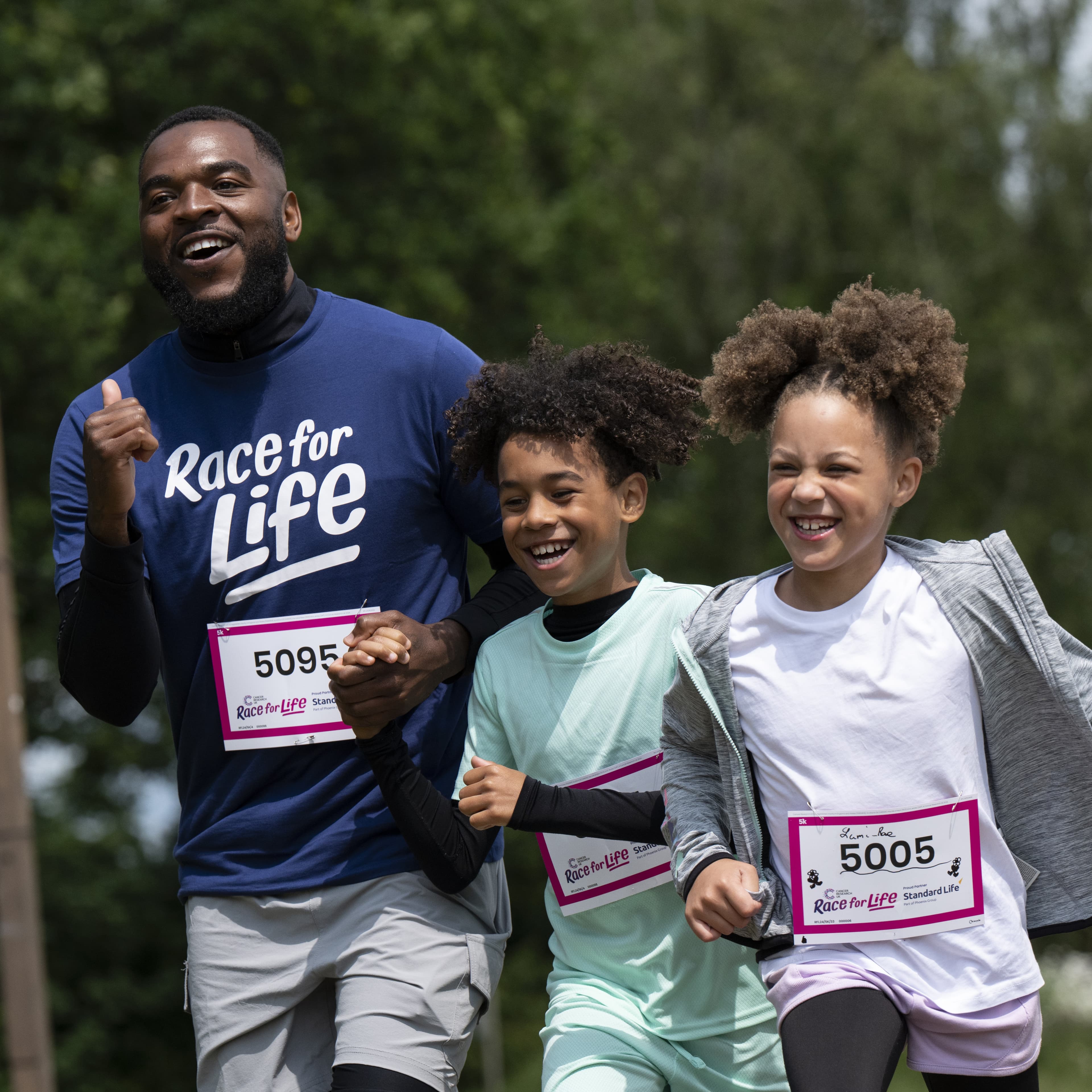 A family of a father and two kids joyfully running the course.